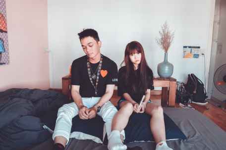 man and woman wearing black shirts sitting on bed